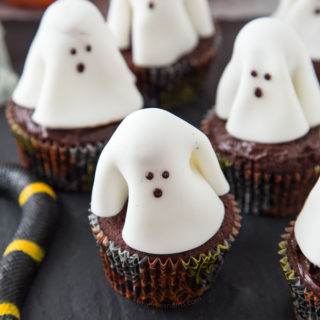A chocolate frosted cupcake with a fondant ghost atop it; these Ghost Cupcakes are treats that adults and kids alike will love! #ad